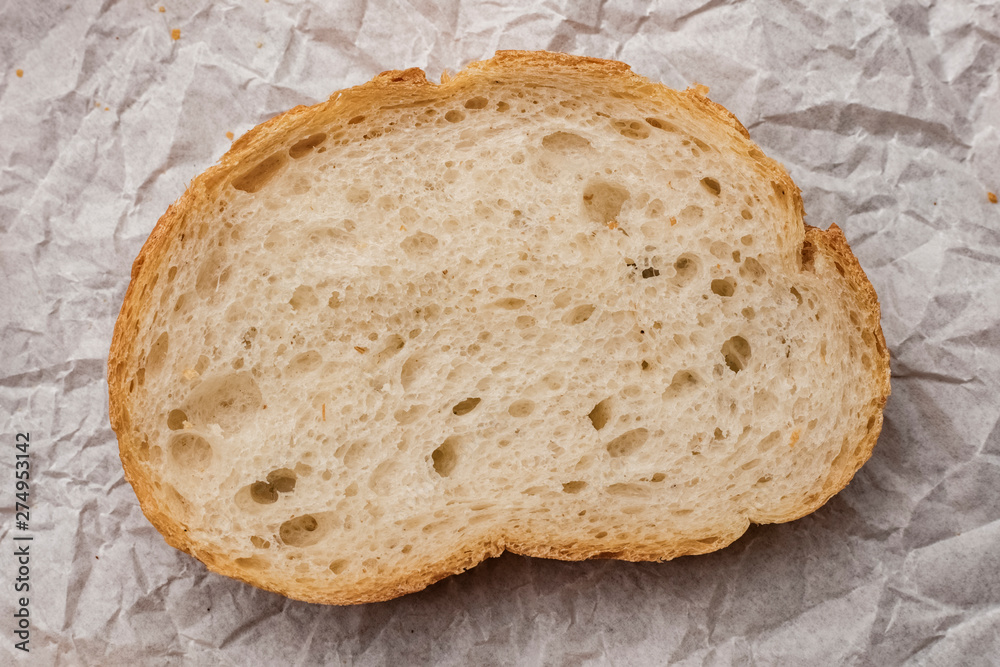 piece of fresh bread on a background of crumpled paper. View top. Close up