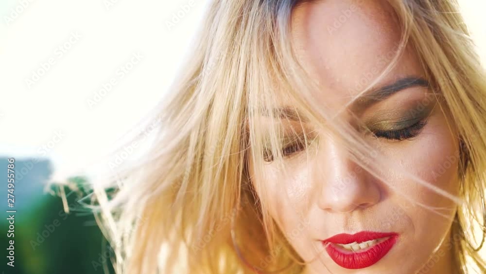 closeup portrait of pretty blonde woman with red lipstick in sunshine outside closeup portrait of pretty blonde woman with red lipstick in sunshine outside