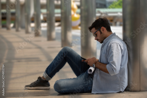 young man using smart while sitting on ground