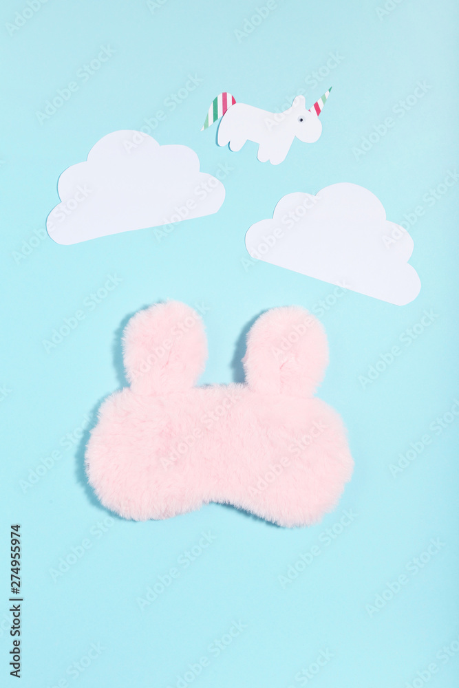 Sleeping mask with paper clouds and unicorn on blue background. Minimalism concept