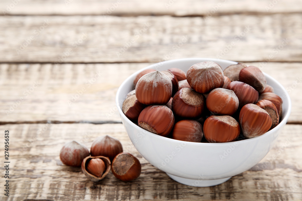 Hazelnuts in bowl on wooden table Hazelnuts in bowl on wooden table