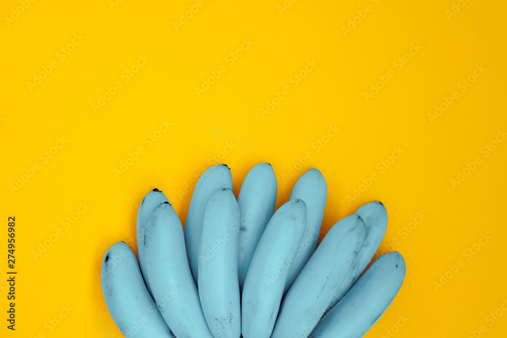 Unusual blue bananas on yellow backdrop top view. Tropical and exotic fruit flat lay on bright background. Healthy vegan and vegetarian diet. Summertime dessert ingredient. Simple, colorful wallpaper - obrazy, fototapety, plakaty 