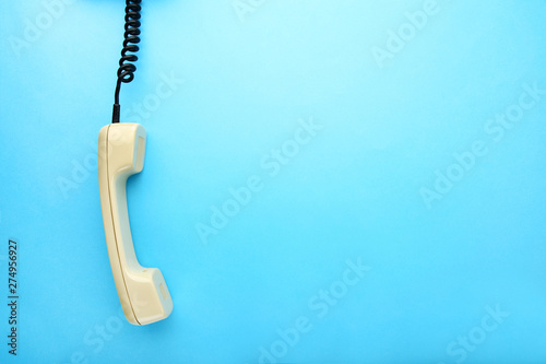 Beige telephone handset on blue background