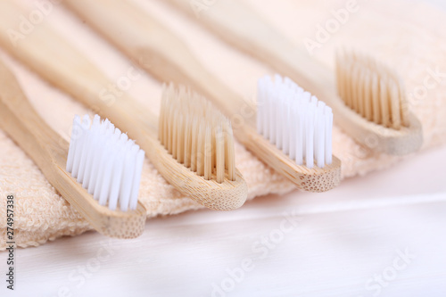 Bamboo toothbrushes with towel on white wooden table