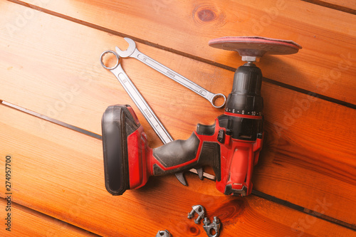 Two wrenches and a power sander are laying on a wooden surface