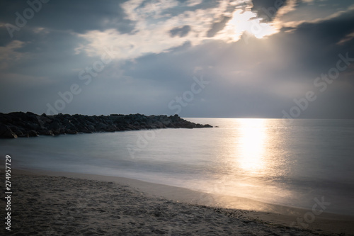 beautiful sandy scenic beach in sunset, with rocky breakwater in long exposure in basque country, france, creative background