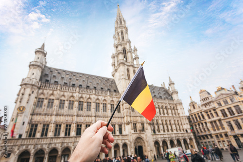 Woman tourist holds in her hand a flag of Belgium against the background of the Grand-Place Square in Brussels, Belgium © LALSSTOCK
