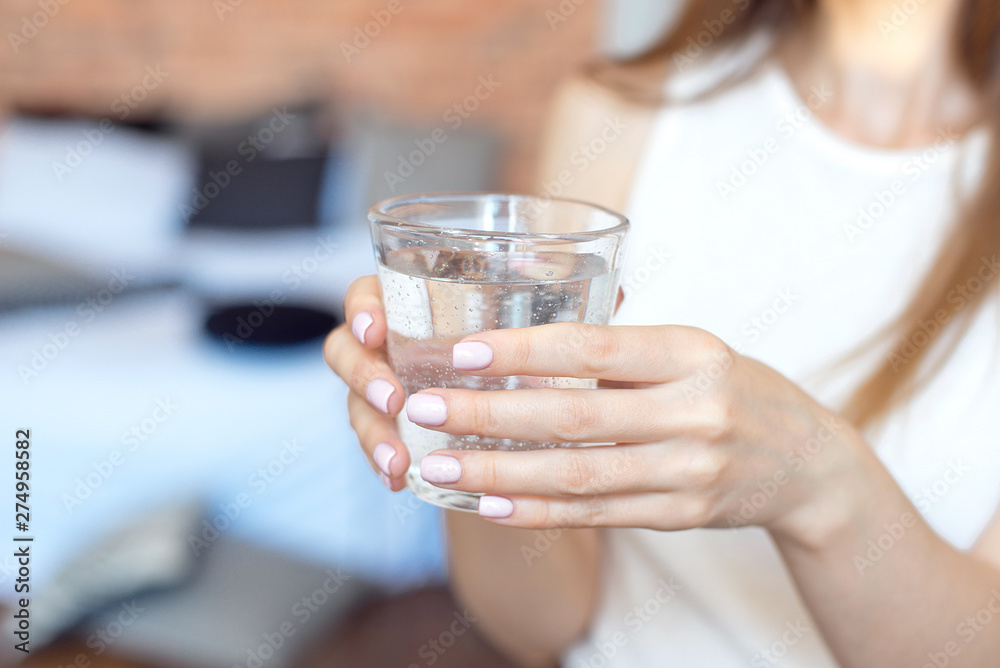 Female hands holding a clear glass of water.A glass of clean mineral water in hands, healthy drink