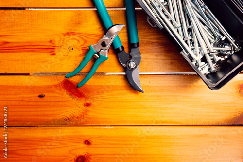 Two pairs of pruning scissors and a tool box are laying on a wooden surface