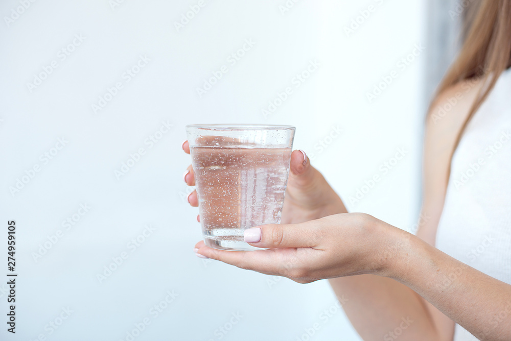 Female hands holding a clear glass of water.A glass of clean mineral water in hands, healthy drink Female hands holding a clear glass of water.A glass of clean mineral water in hands, healthy drink