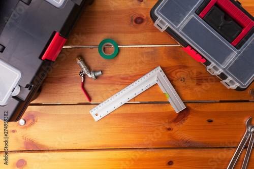 A ruler, pipe, tape, and tool boxes are laying on a wooden surface