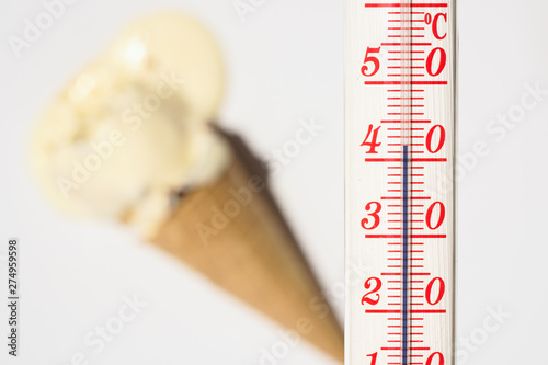 Thermometer during hot weather with melted ice creams in background