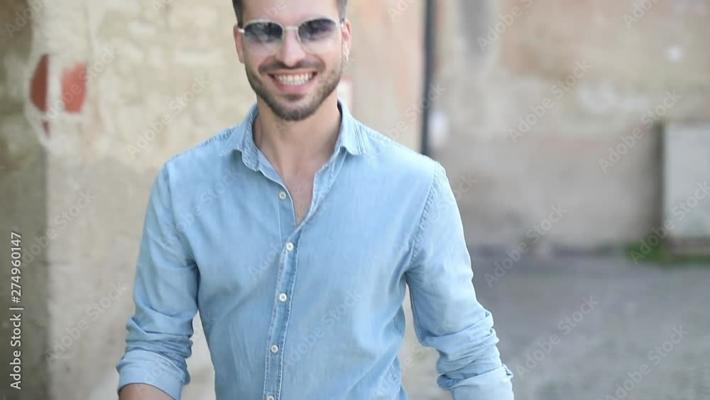 young casual man cheers and celebrates a win while walking on the streeets of an old town young casual man cheers and celebrates a win while walking on the streeets of an old town