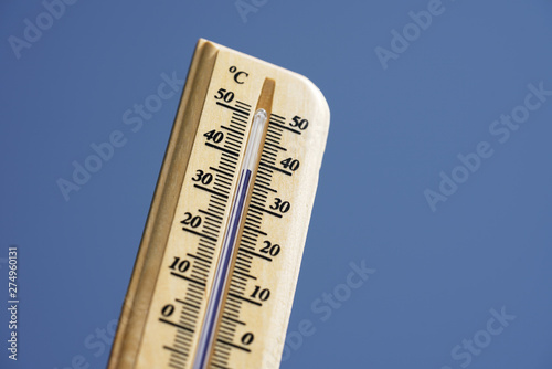 Thermometer during hot weather with sky in background