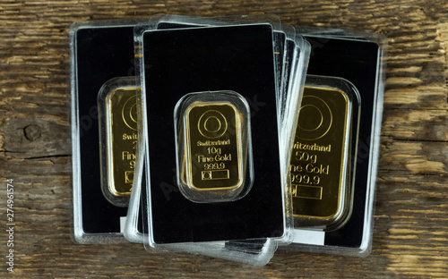 Several gold bars of different weight in plastic packaging on a wooden background. photo