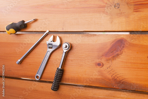 A various assortment of tools is laying on a wooden surface