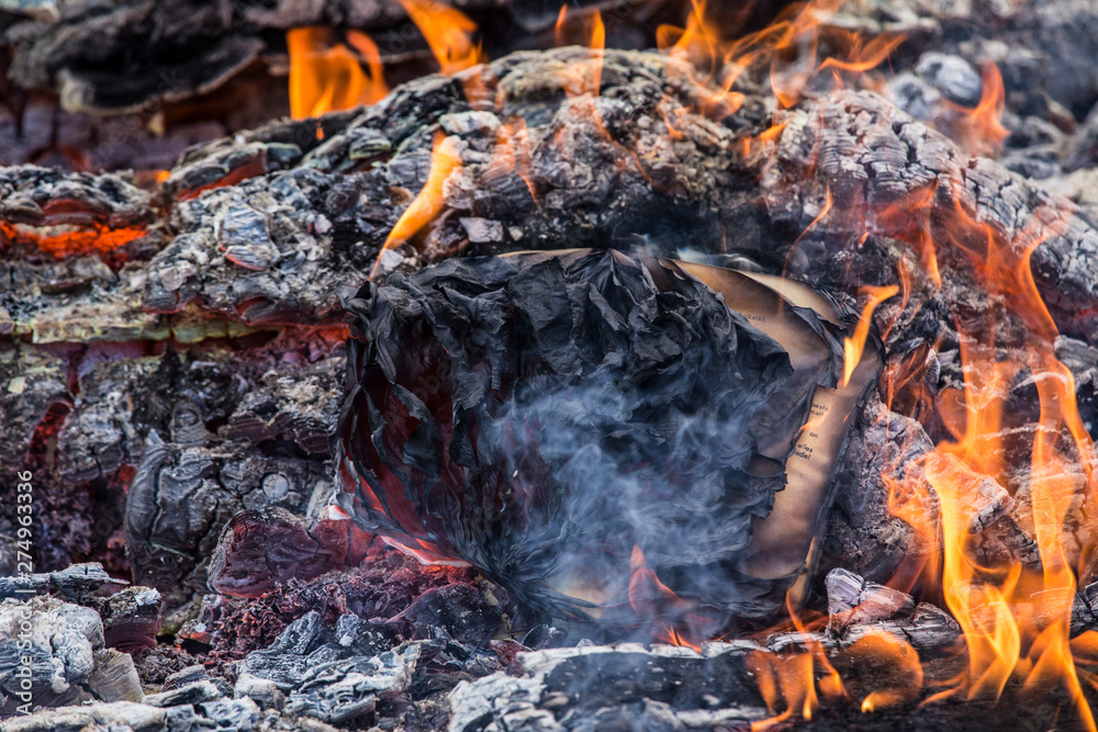 Close up view of open burned book with charred crumpled paper sheets. The end concept.