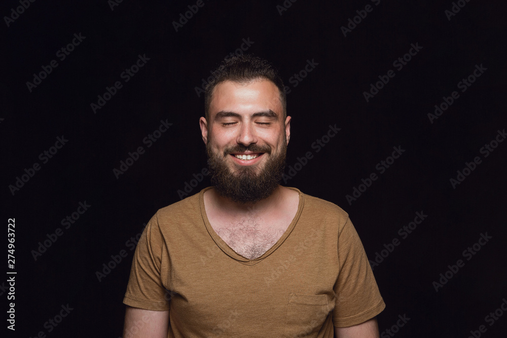 Close up portrait of young man isolated on black studio background. Photoshot of real emotions of male model with closed eyes. Thinking and smiling. Facial expression, human emotions concept. Close up portrait of young man isolated on black studio background. Photoshot of real emotions of male model with closed eyes. Thinking and smiling. Facial expression, human emotions concept.