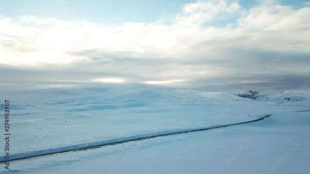 Lone car maneuvers snow-covered thoroughfare in northern location
