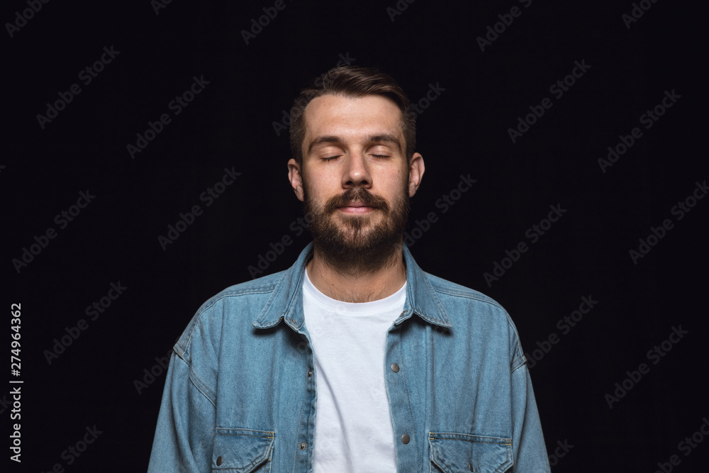 Close up portrait of young man isolated on black studio background. Photoshot of real emotions of male model with closed eyes. Thinking and smiling. Facial expression, human emotions concept. Close up portrait of young man isolated on black studio background. Photoshot of real emotions of male model with closed eyes. Thinking and smiling. Facial expression, human emotions concept.