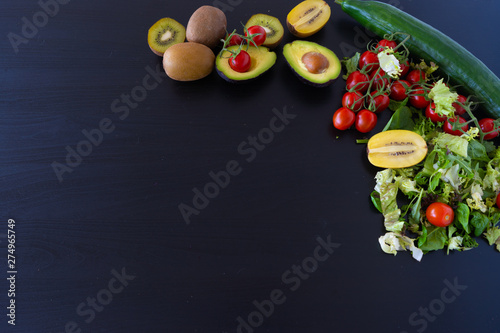 kiwi, lettuce, tomatoes, avocado and cucumber on the black background © Viktoras