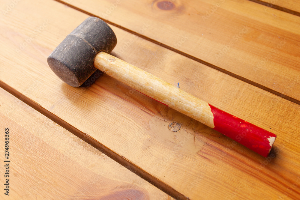 A black mallet is laying on a wooden surface