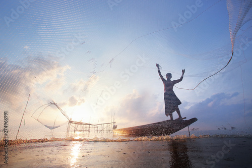 Fishermen on boat fishing with a large fishnet.Silhouette scene of the morning. photo