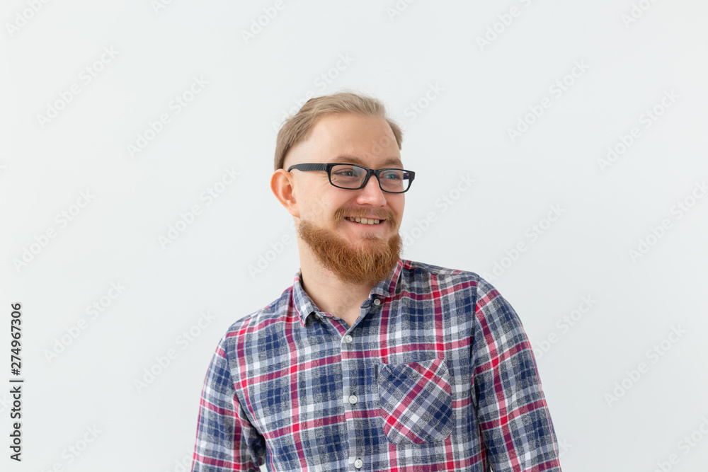 Fototapeta premium Positive emotions and people concept - young bearded man in glasses is smiling on white background