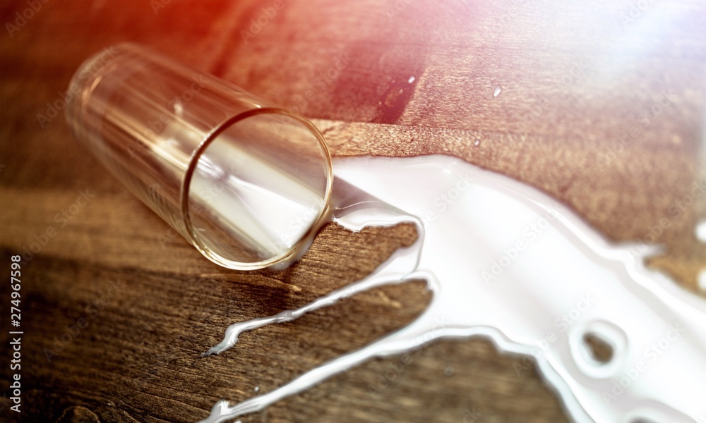 Fototapeta premium Milk spilled from glass on oak wooden surface