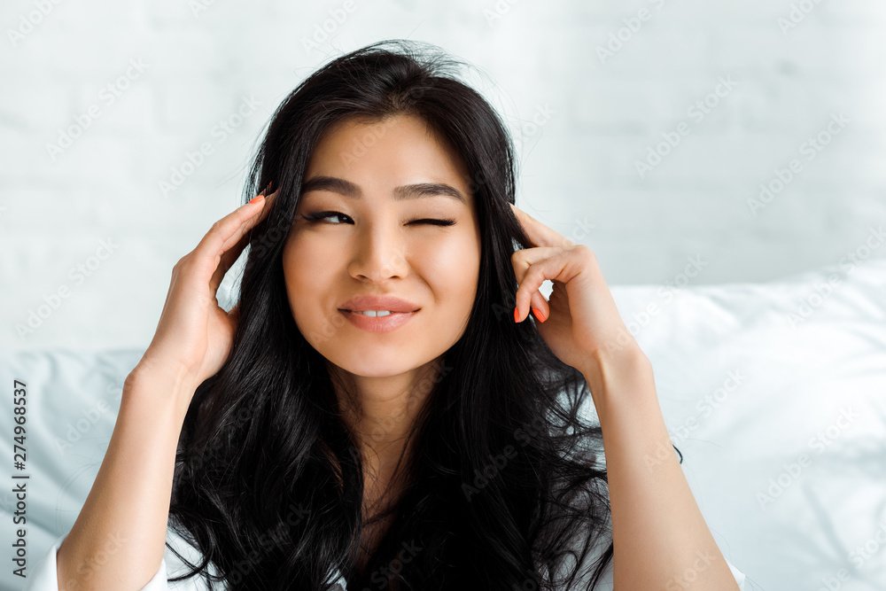 happy thai woman smiling at touching hair while winking eye happy thai woman smiling at touching hair while winking eye