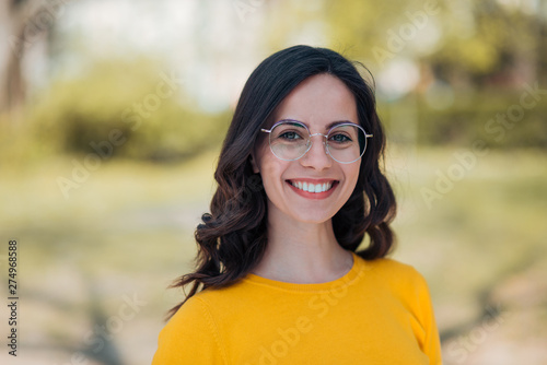 Head shot of a young beautiful woman with toothy smile outdoors.