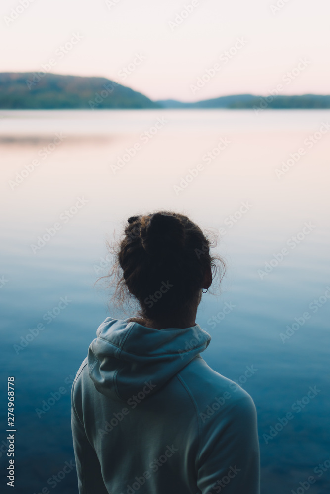 Woman gazing at a Serene Swedish Lake in Summer Woman gazing at a Serene Swedish Lake in Summer