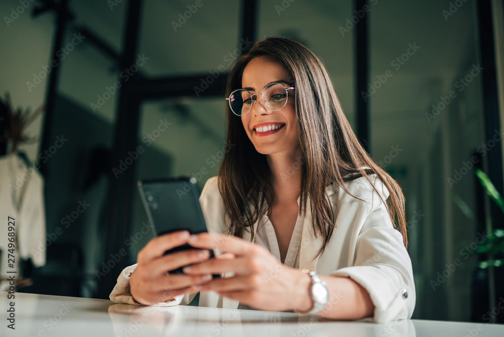 © bnenin - Portrait of a smiling young businesswoman using phone at work. © bnenin - Portrait of a smiling young businesswoman using phone at work.