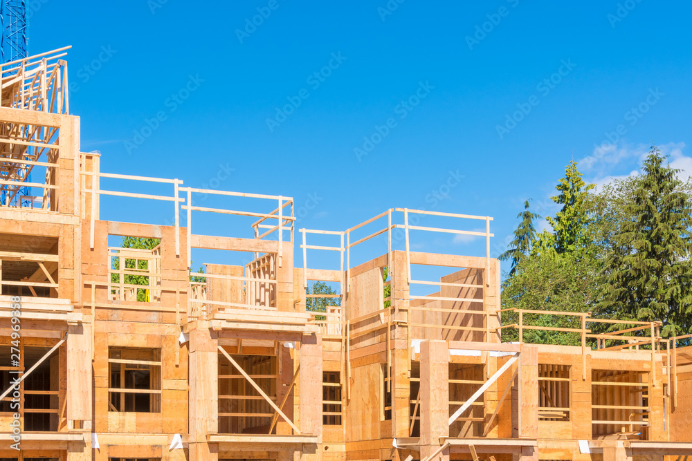 New condo building under construction on blue sky and trees background New condo building under construction on blue sky and trees background
