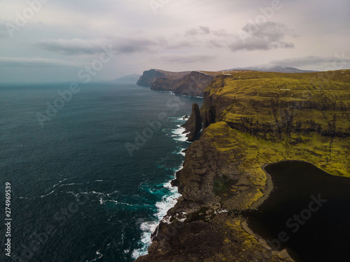 Aerial panorama view of famous Sorvagsvatn Lake / Leitisvatn Lake from above during a moody spring evening with Bosdalafossur waterfall and dark blue sea (Faroe Islands, Denmark, Europe)