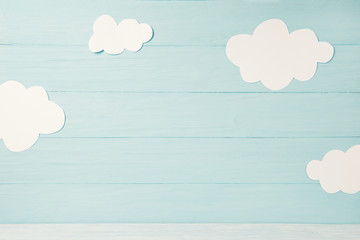 Cute children or baby card, white clouds on the light blue wooden background, tonned