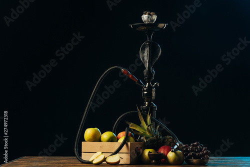 Fototapeta Naklejka Na Ścianę i Meble -  fresh tasty fruits and hookah on wooden surface isolated on black