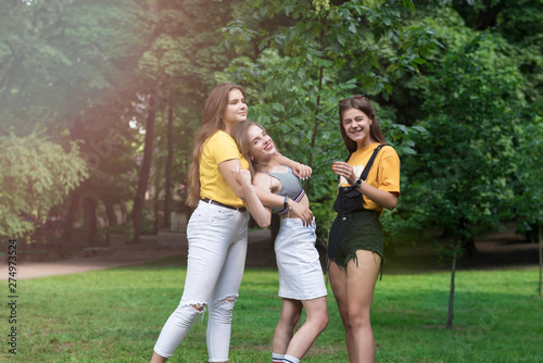 Three nice teen girls having fun in the park. Excellent sunny weather. Summer concept. Hugging. Lifestyle. Trendy Hipster Girls