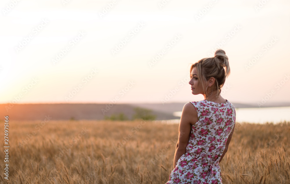 young seductive rural blond hair woman in dress on the yellow wheat field on the sunset, lake on the background young seductive rural blond hair woman in dress on the yellow wheat field on the sunset, lake on the background