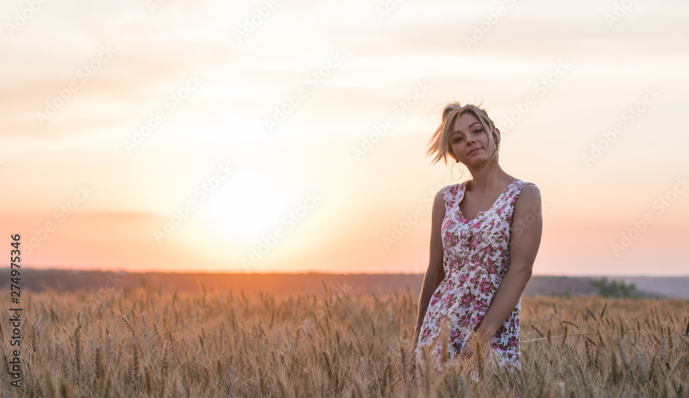 young seductive rural blond hair woman in dress on the yellow wheat field on the sunset, lake on the background young seductive rural blond hair woman in dress on the yellow wheat field on the sunset, lake on the background