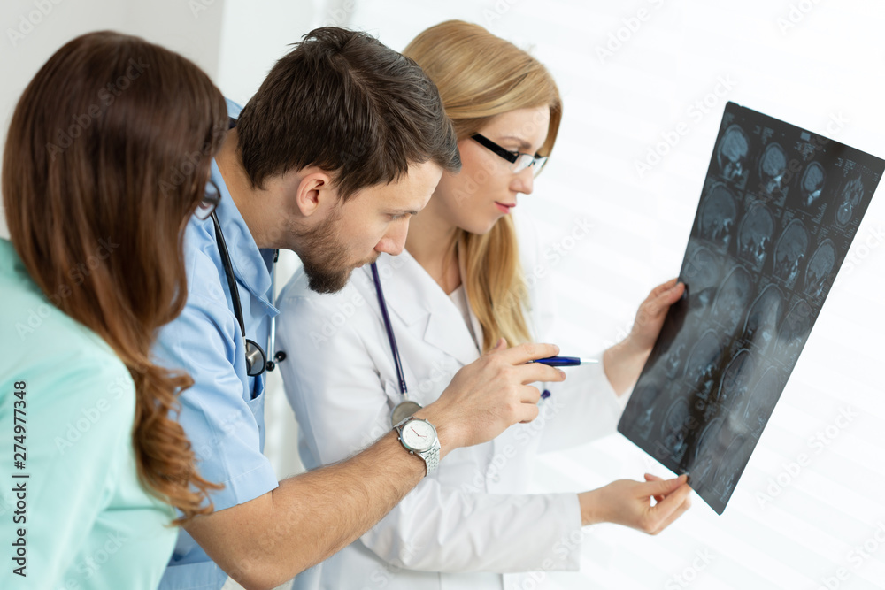 Handsome young doctor pointing at x-ray exam during medical consultation Handsome young doctor pointing at x-ray exam during medical consultation