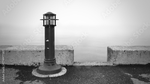 Phare sur le quai et brume sur le lac
