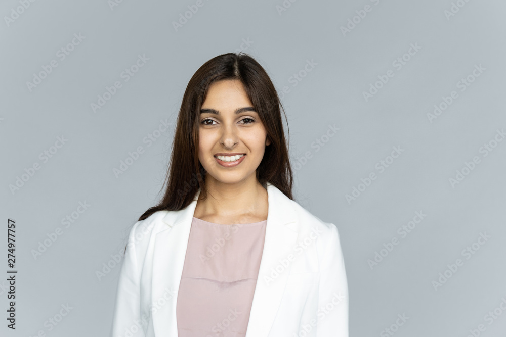 Smiling indian young businesswoman wear white suit looking at camera isolated on grey studio background, happy attractive confident hindu business lady professional head shot close up portrait Smiling indian young businesswoman wear white suit looking at camera isolated on grey studio background, happy attractive confident hindu business lady professional head shot close up portrait