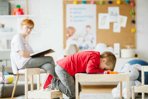 Cute little boy with ADHD during session with professional therapist photo