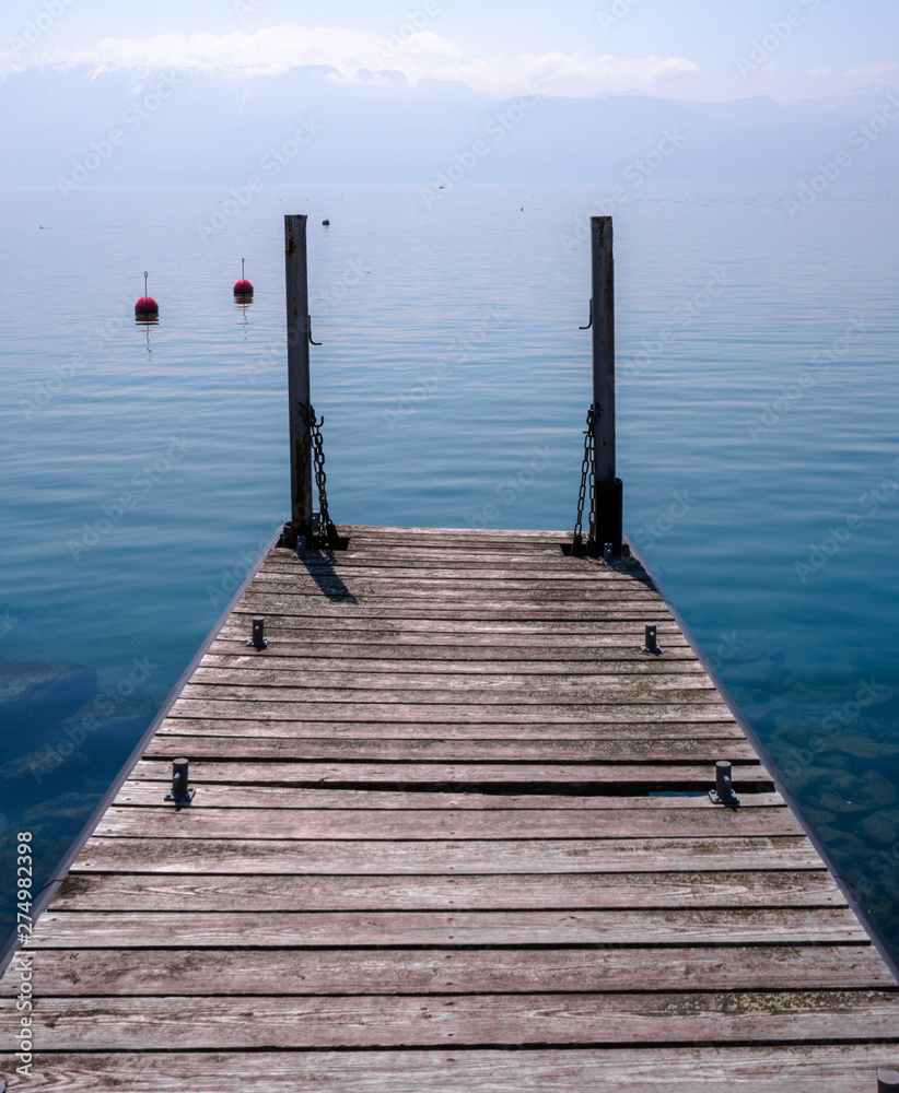 Fototapeta premium Boat Jetty Dock Boardwalk Clear Water Lake with Mountain Backdrop in Lausanne, Switzerland
