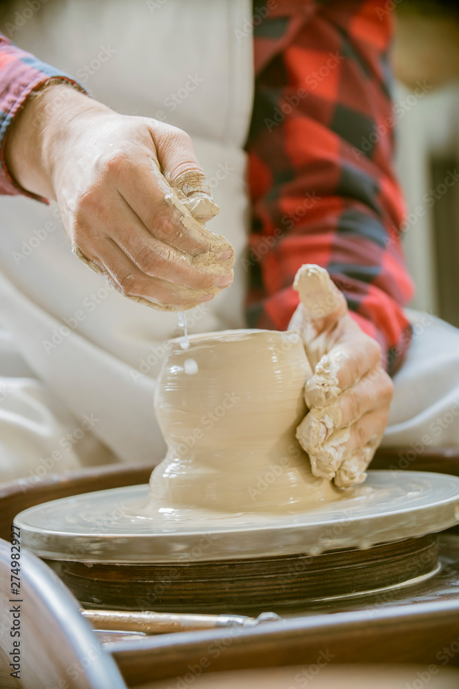close-up of a Potter's hand sculpts a pot pitcher of clay on a Potter's wheel