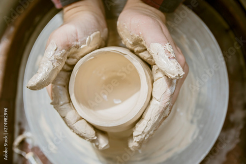 close-up of a Potter's hand sculpts a pot pitcher of clay on a Potter's wheel