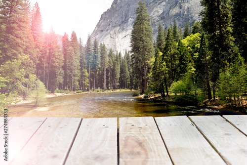 Wooden shelf with nature forest and mountain range background, calm river through woodland trees