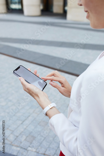Mid section closeup of young businesswoman holding smartphone outdoors in urban area, copy space