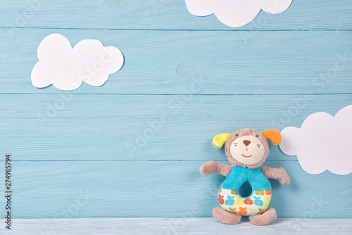 Cute toy puppy beanbag on a blue wooden background with white clouds, baby card